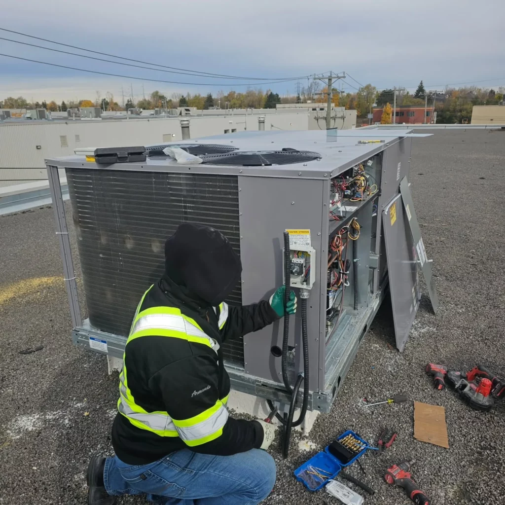 Electrician connecting a 600 V rooftop heat pump at Soccer IQ in Saint-Léonard