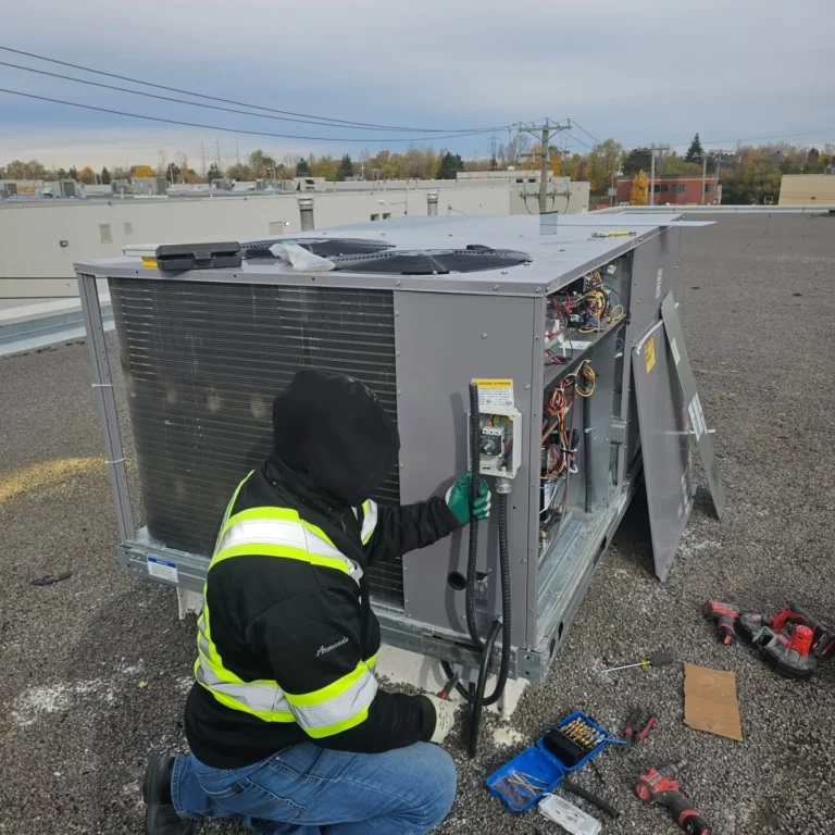 Electrician connecting a 600 V rooftop heat pump at Soccer IQ in Saint-Léonard