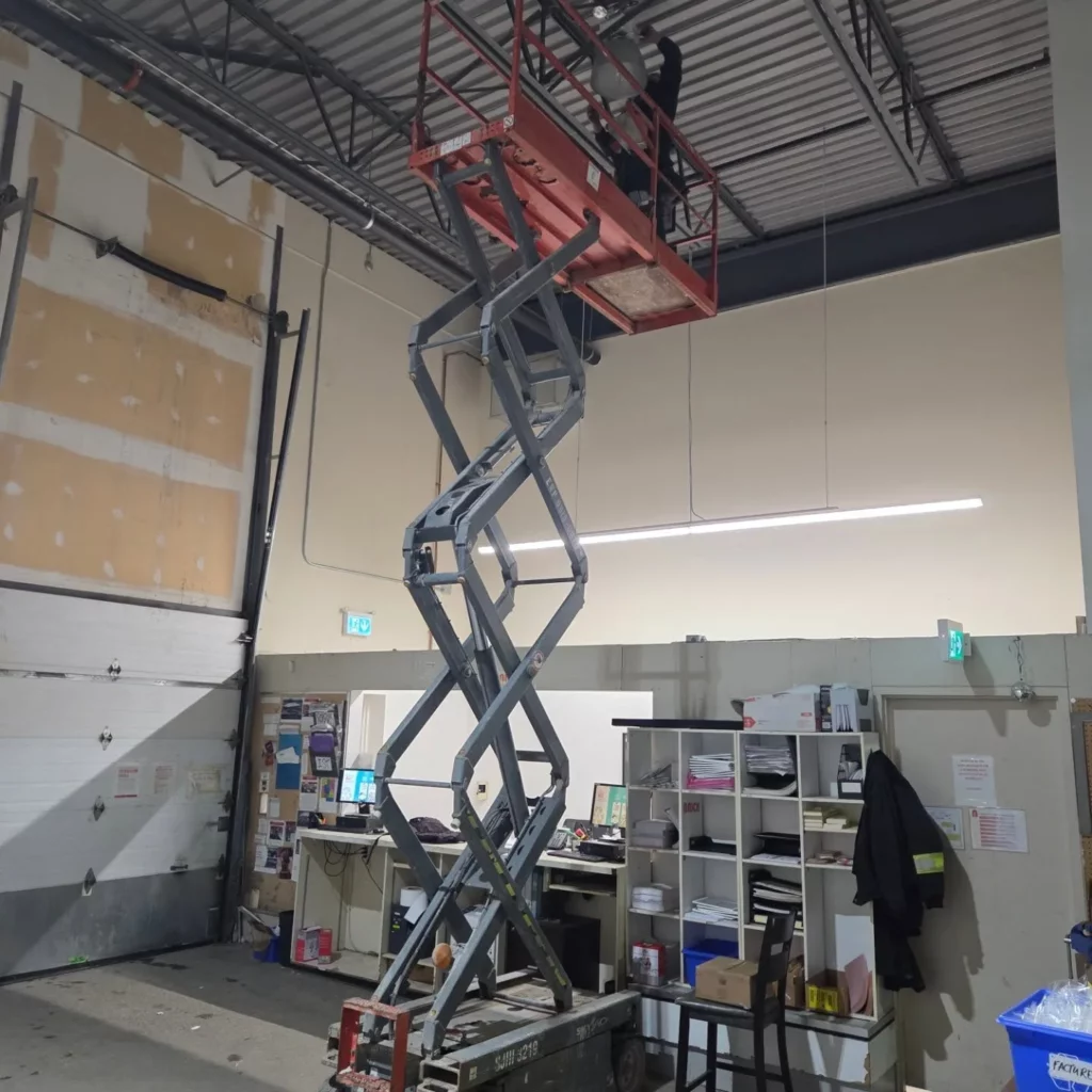 Scissor lift used to replace warehouse fixtures with LED lighting